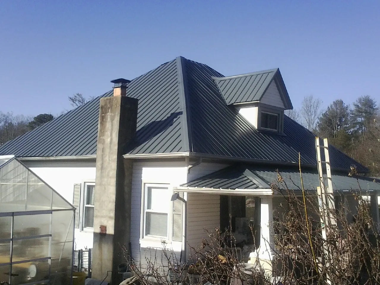 Dark blue standing seam metal roof on a white farmhouse with dormer — Slate & Tile Roof Repair by Roofing Brothers in Watonga