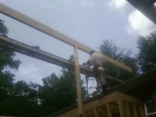 Carpenter setting a ridge beam over a new addition frame — Ice Dam Removal by Roofing Brothers in Watonga