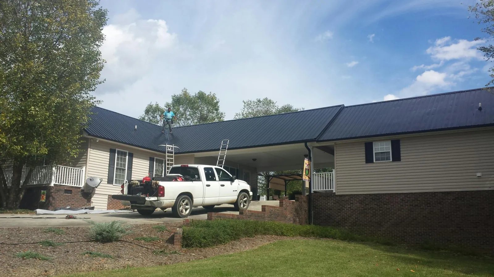 Black metal roof over a home and attached breezeway with ladders set in Watonga