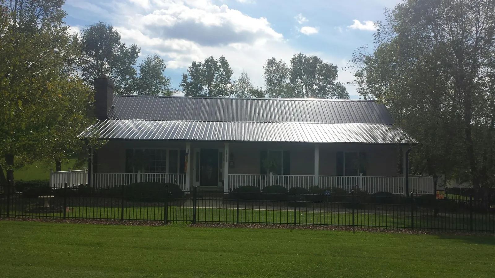 Gray metal roof on a brick ranch with a full width front porch — Gutter Guard Installation work by our crew in Watonga