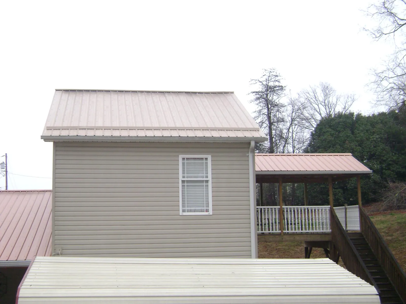 Tan metal roofs on a two story addition and attached porch, from a Roof Replacement job in Watonga