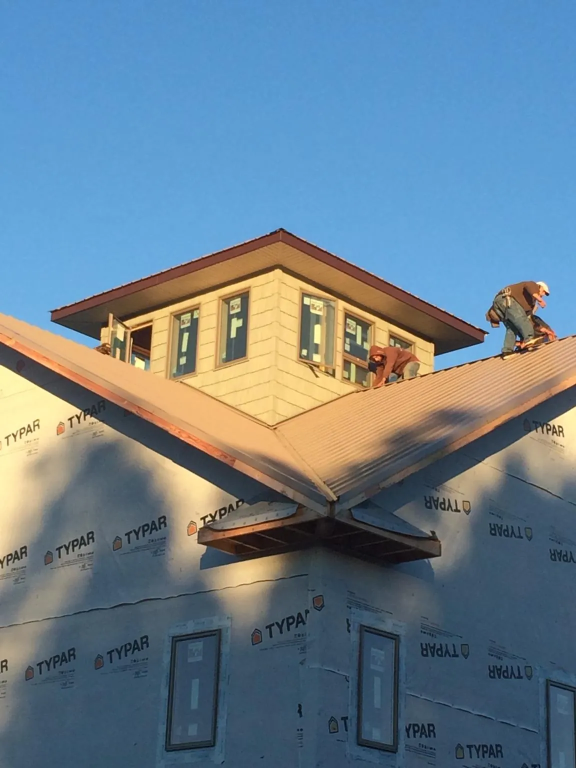 Roofers working around a rooftop cupola on a new metal roof at sunset — Roof Waterproofing in Watonga by Roofing Brothers